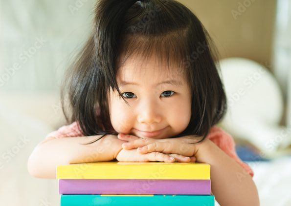 little girl leaning on a stack of books